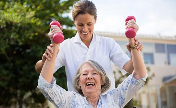 Nurse helping old woman to exercise