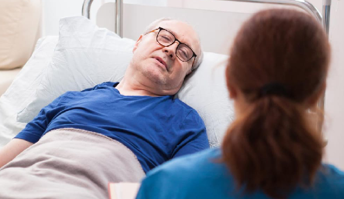 Back view of a nurse sitting in a chair, talking with a pensioner in a nursing home.