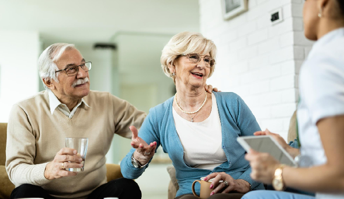 Woman Her Husband Communicating With Healthcare Worker During Home Visit